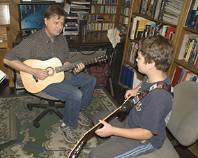 Photo of a guitar student and instructor.
